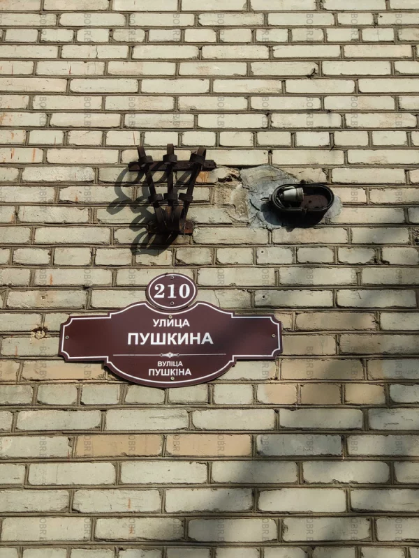 Красивая табличка с названием улицы и номером дома но объясните пожалуйста что там делает Ржавый флагшток и патрон от лампочки?