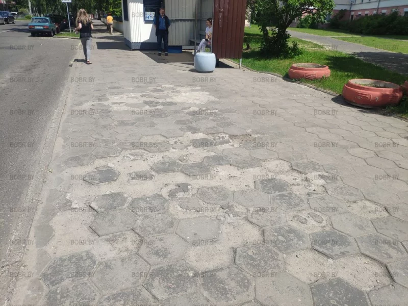 Выбоины на тротуарной плитке у остановки напротив райисполкома.